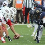 Rival football teams face off at the start of an action-packed game on the field.