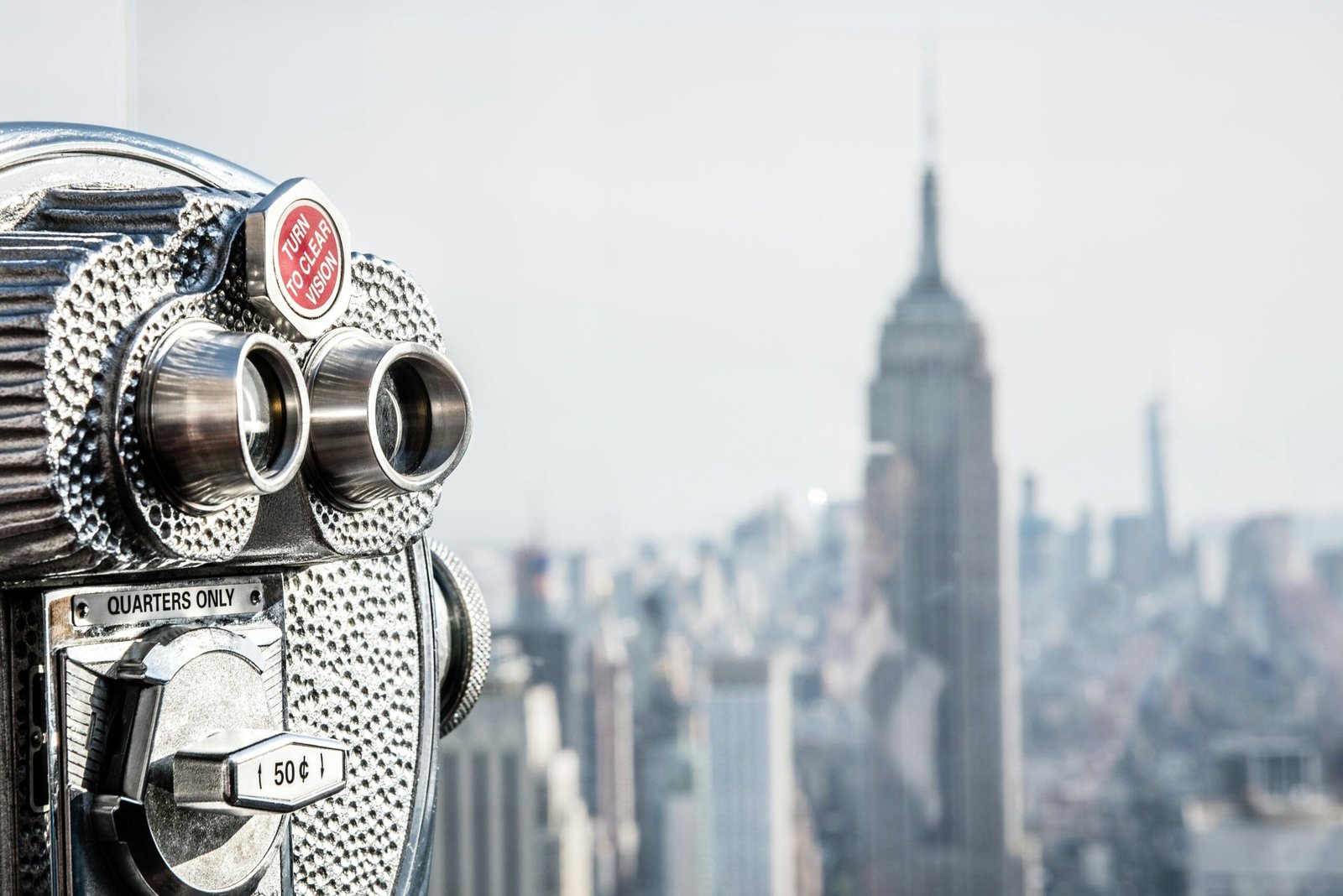 Coin-operated binoculars on a New York City observation deck with the Empire State Building in view.